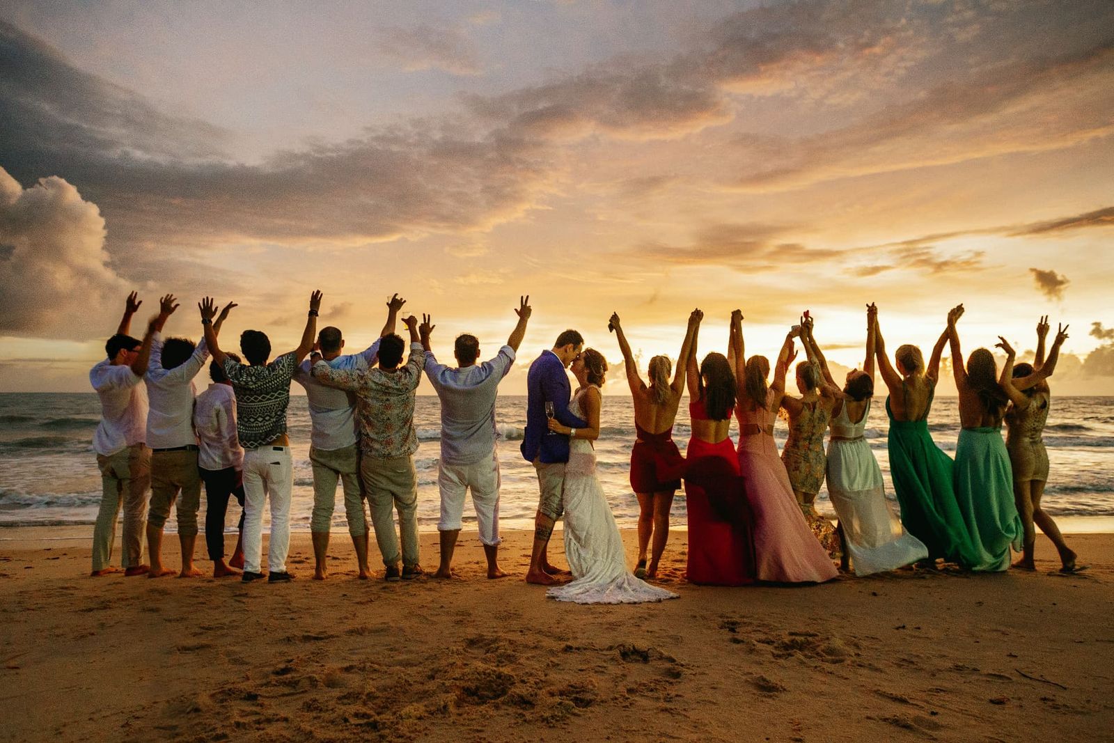 Group of young people celebrating together on a beach at sunset
