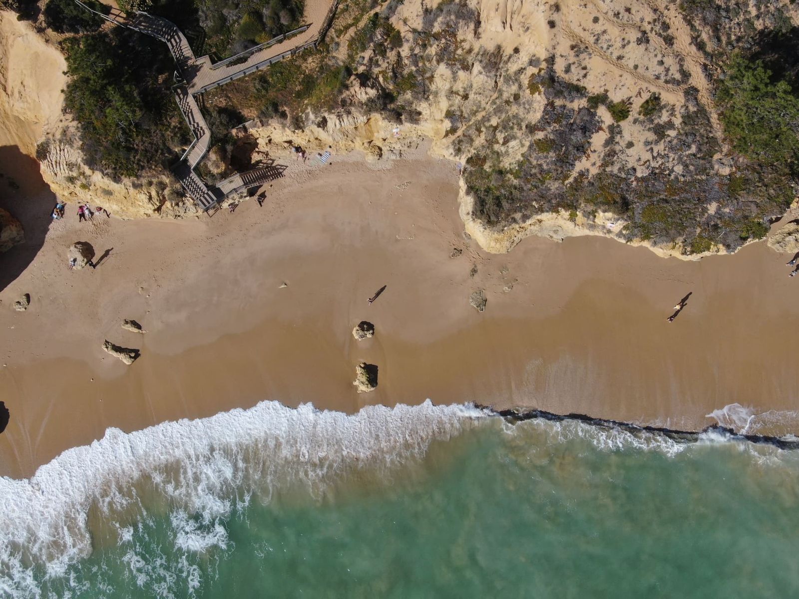 Wooden staircase down a cliff to a sandy beach cove