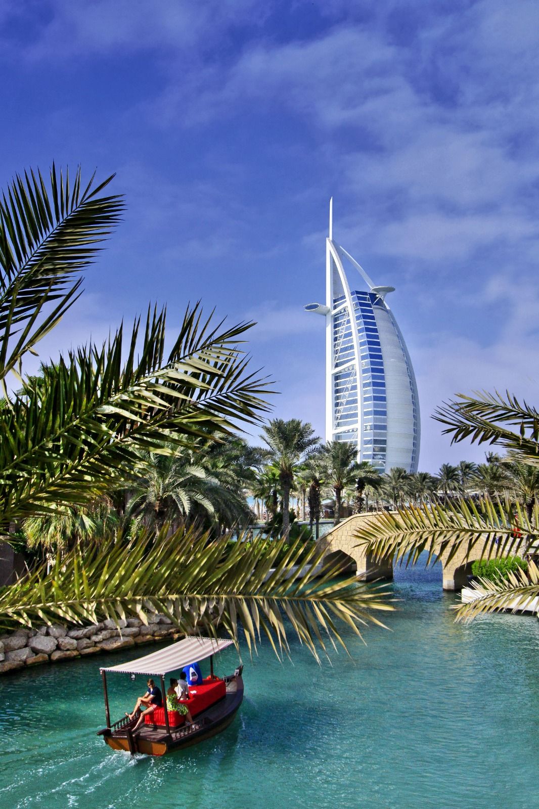 Traditional boat on a turquoise Dubai canal with the Burj Al Arab behind