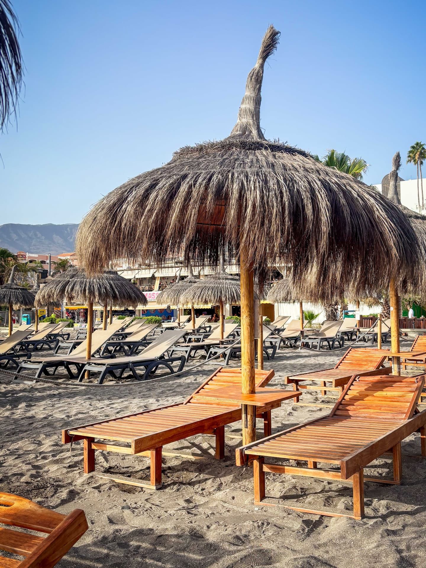 Straw umbrellas and wooden sun loungers on the sand