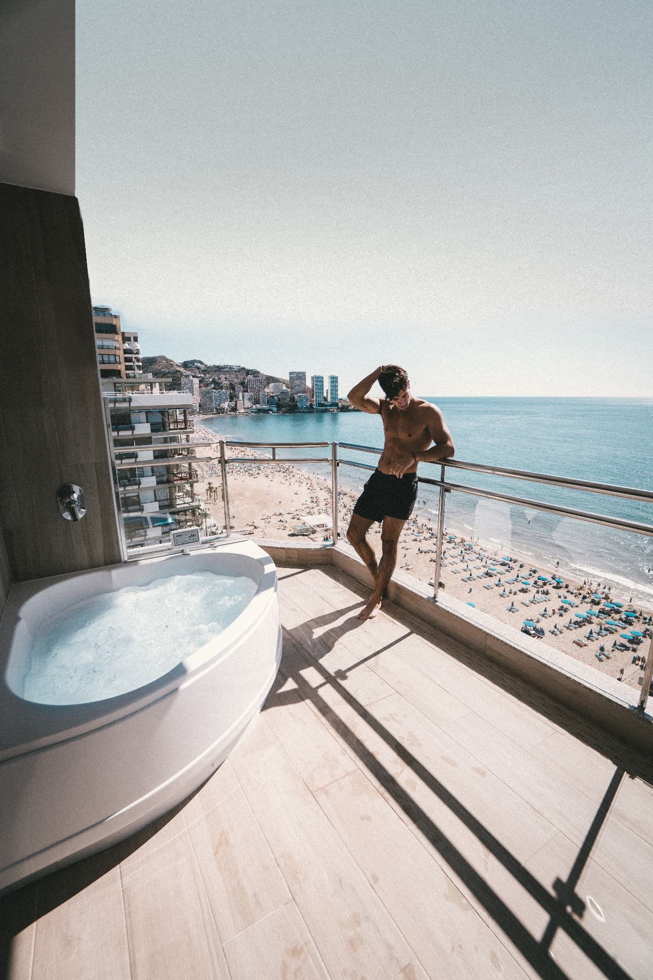Balcony jacuzzi overlooking a wide sandy beach and hotels