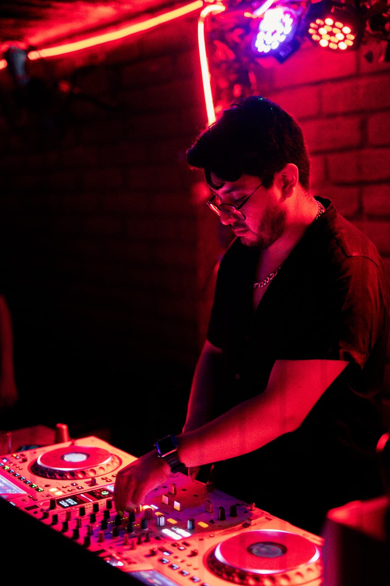 DJ mixing under red and purple club lighting