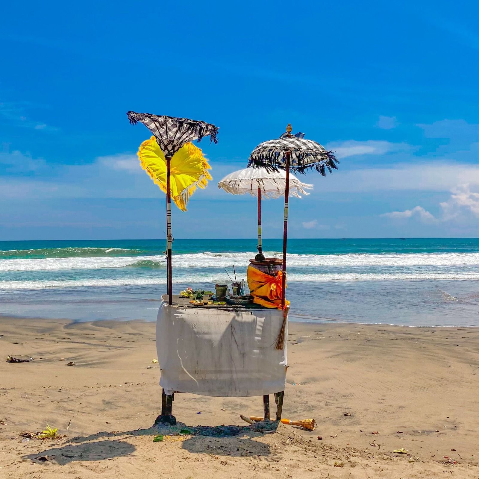 Colourful beach shrine with umbrellas on Thai sand under blue sky