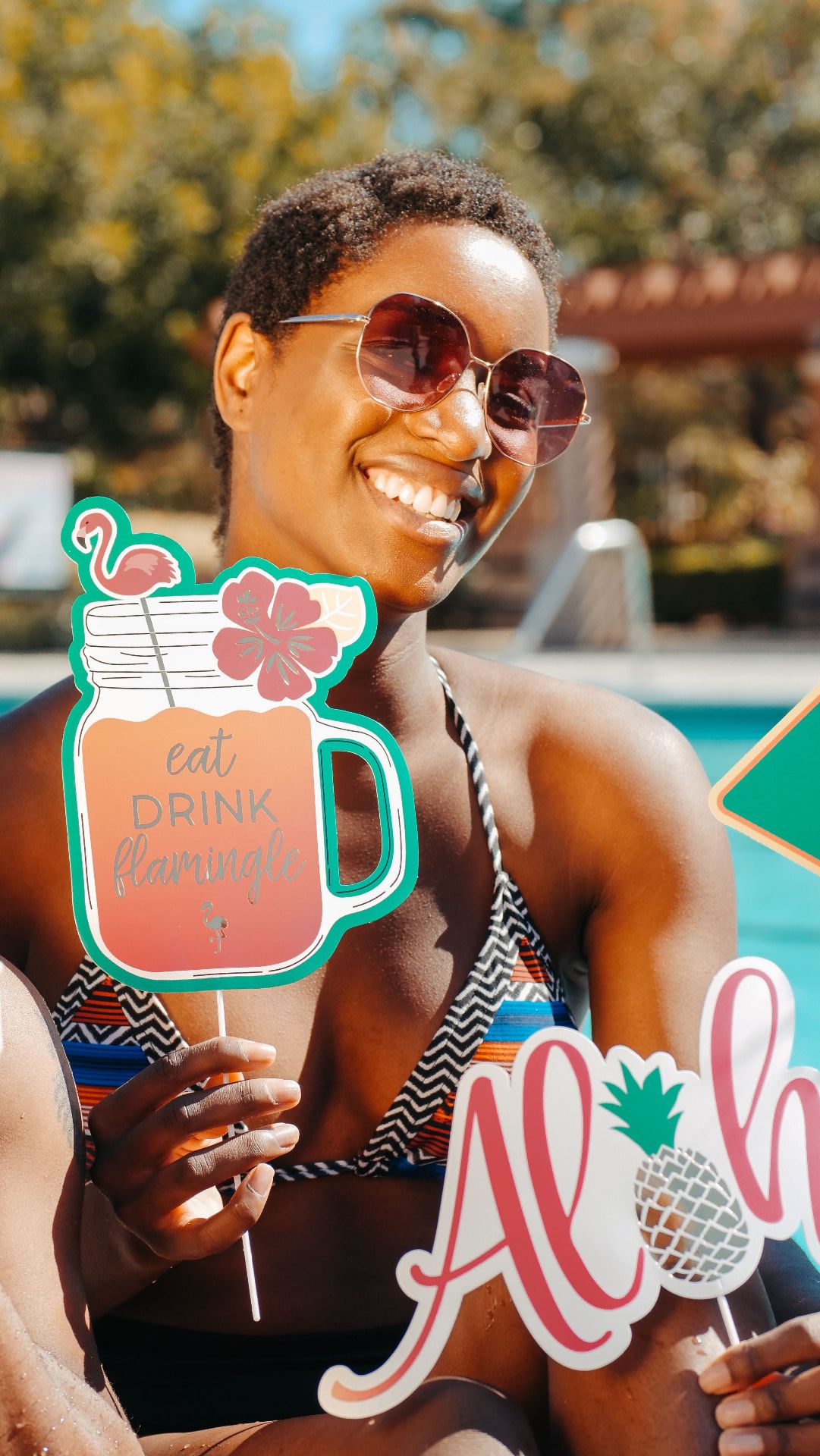Woman by a pool holding colourful summer photo props